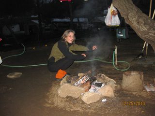 Woman tending a campfire at night.