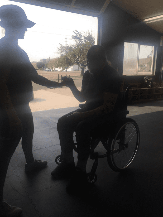 Person assisting wheelchair user inside building.