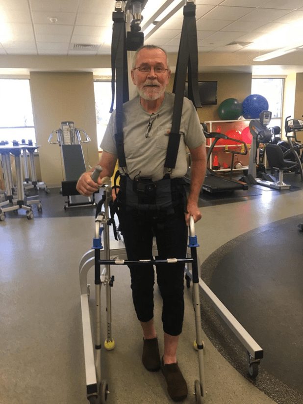 Man using rehabilitation harness in therapy gym.