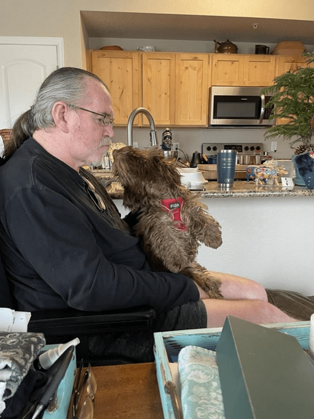 Man and dog sitting in kitchen.